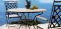 Tavolo in ferro battuto con piano in pietra e sedie, modello Capri Manutti