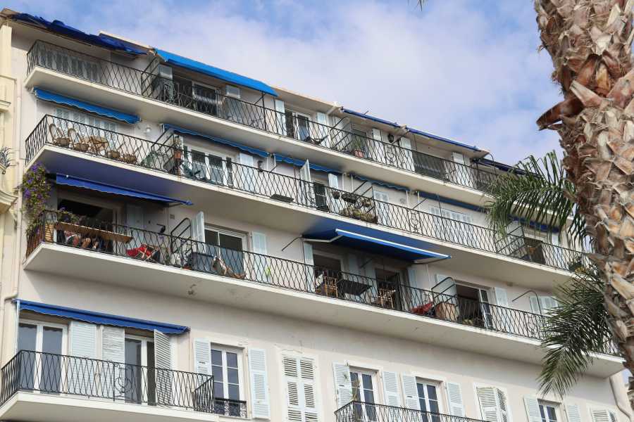 Condominio con balconi e tende da sole blu installate su diversi piani.