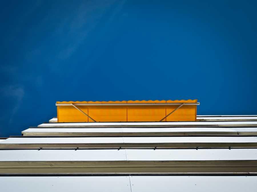 Tenda da sole gialla aperta su edificio vista dal basso contro cielo blu.
