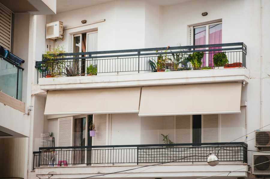 Balconi di condominio con tende da sole beige montate sulla facciata.