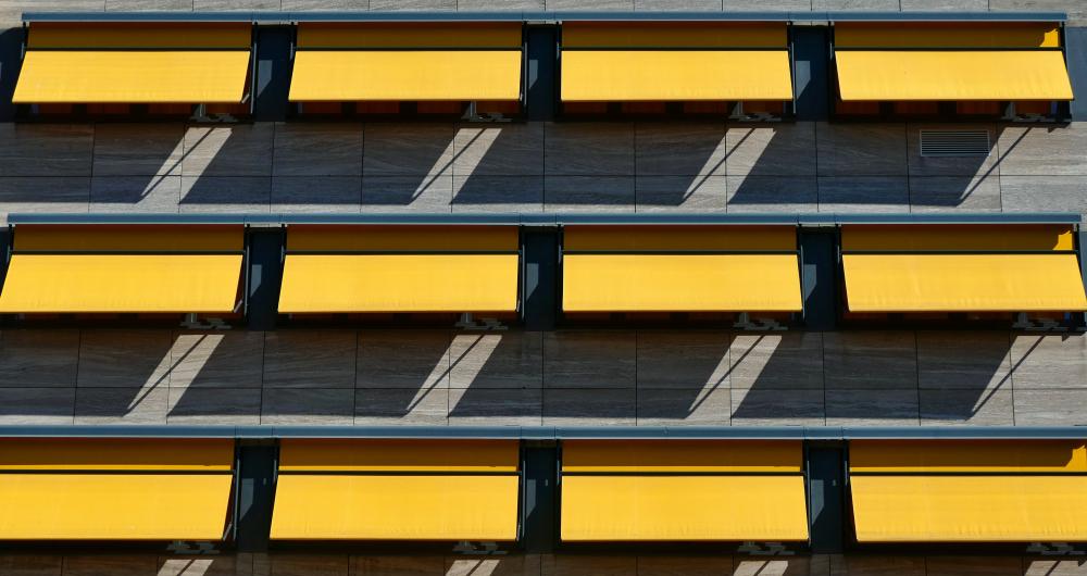 Serie di tende da sole gialle installate su una facciata moderna.