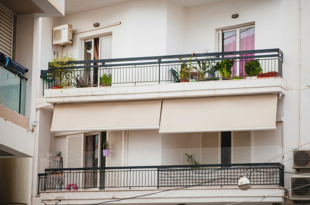 Tende da sole chiare installate sotto i balconi di un edificio residenziale.