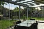 Serra bioclimatica vetrata con vista sul giardino, progettata per sfruttare la luce naturale senza rinunciare alla ventilazione.